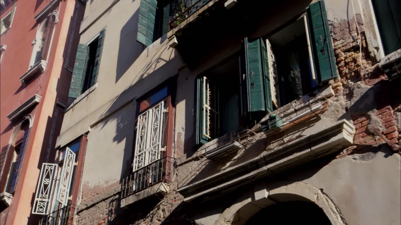 Facciata storica di edificio europeo con mura logore e persiane