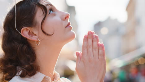 Portrait-of-woman-praying-with-closed-eyes-to-God-asking-for-blessing,-help,-forgiveness-outdoors