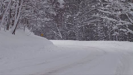 un coche viaja por una carretera de montaña nevada