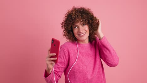 smiling young woman listening to music with smartphone in studio