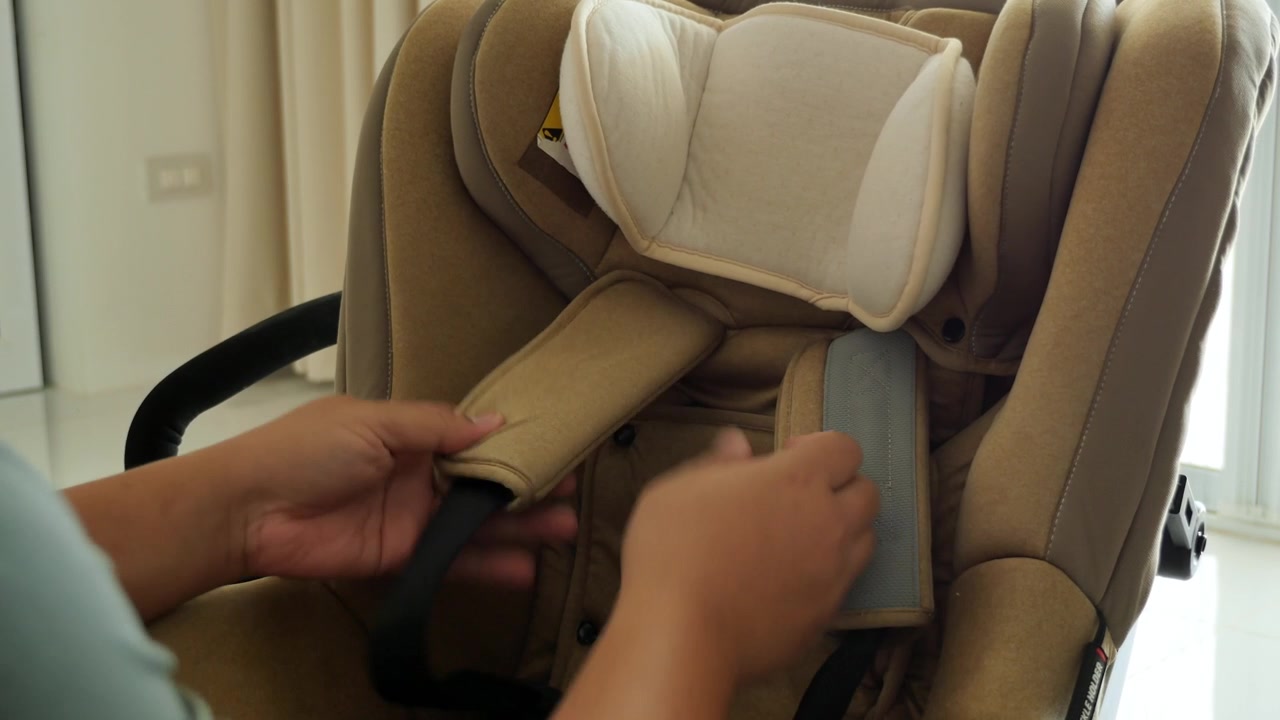 Una persona ajusta los cojines en una silla de coche para niños en un área luminosa. Perfecto para tutoriales de crianza o demostraciones de seguridad.