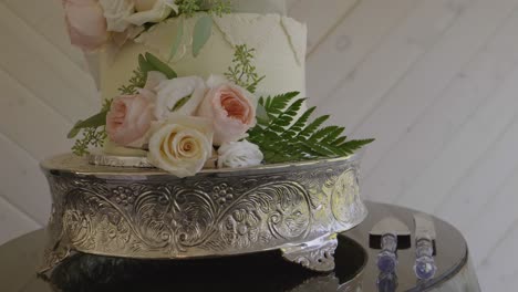 Hermoso-Pastel-De-Bodas-Decorado-Con-Flores-Y-Hojas-Naturales,-Montado-Sobre-Una-Base-De-Plata-Barroca