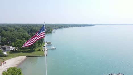 Flag-of-USA-waving-on-pier-of-New-Baltimore-town,-aerial-view