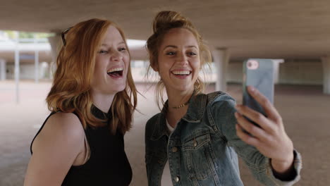 dos hermosas mujeres jóvenes usando un teléfono inteligente posando para una foto selfie haciendo caras alegres y divertidas