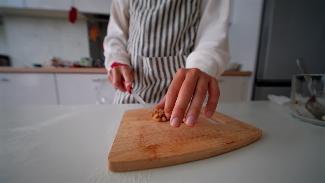 Primo piano di una persona che trita noci su un tagliere in cucina