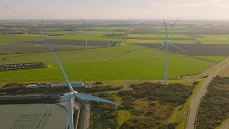 aerial slow motion shot of wind turbines and traffic on a road in a rural area of the netherlands on a beautiful sunny day around sunset