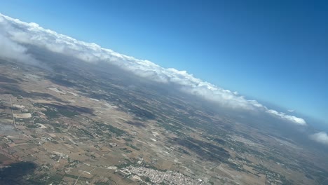 vista aérea de la cabina durante un giro a la izquierda del avión acercándose al aeropuerto de palma de mallorca, con una capa de pocas nubes.