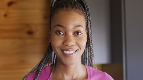 Portrait-of-happy-african-american-woman-looking-at-camera-and-smiling-in-log-cabin,-slow-motion