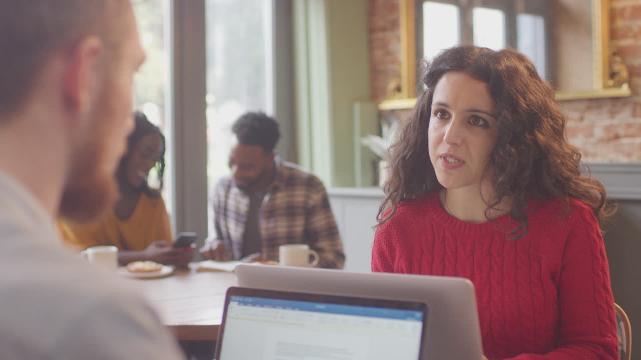 Coppia di professionisti con i laptop che si incontrano e lavorano insieme in una caffetteria
