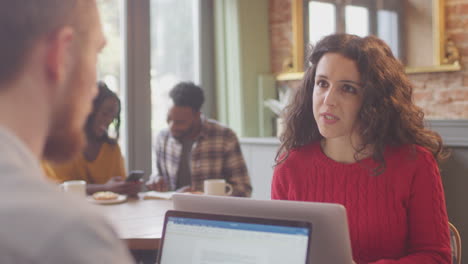 pareja de negocios con computadoras portátiles reuniéndose y trabajando en una cafetería juntos