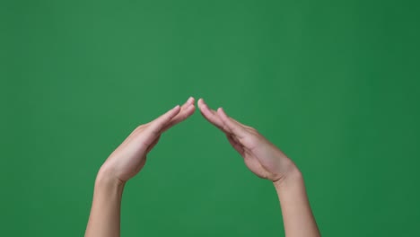 hands making house frame gesture over green screen