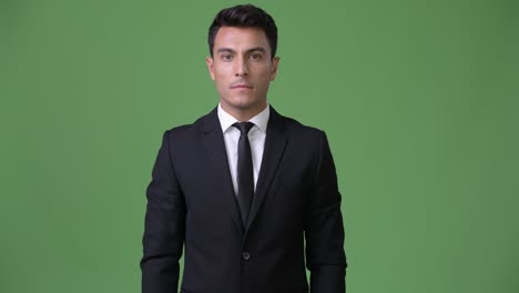 joven y guapo hombre de negocios hispano contra un fondo verde