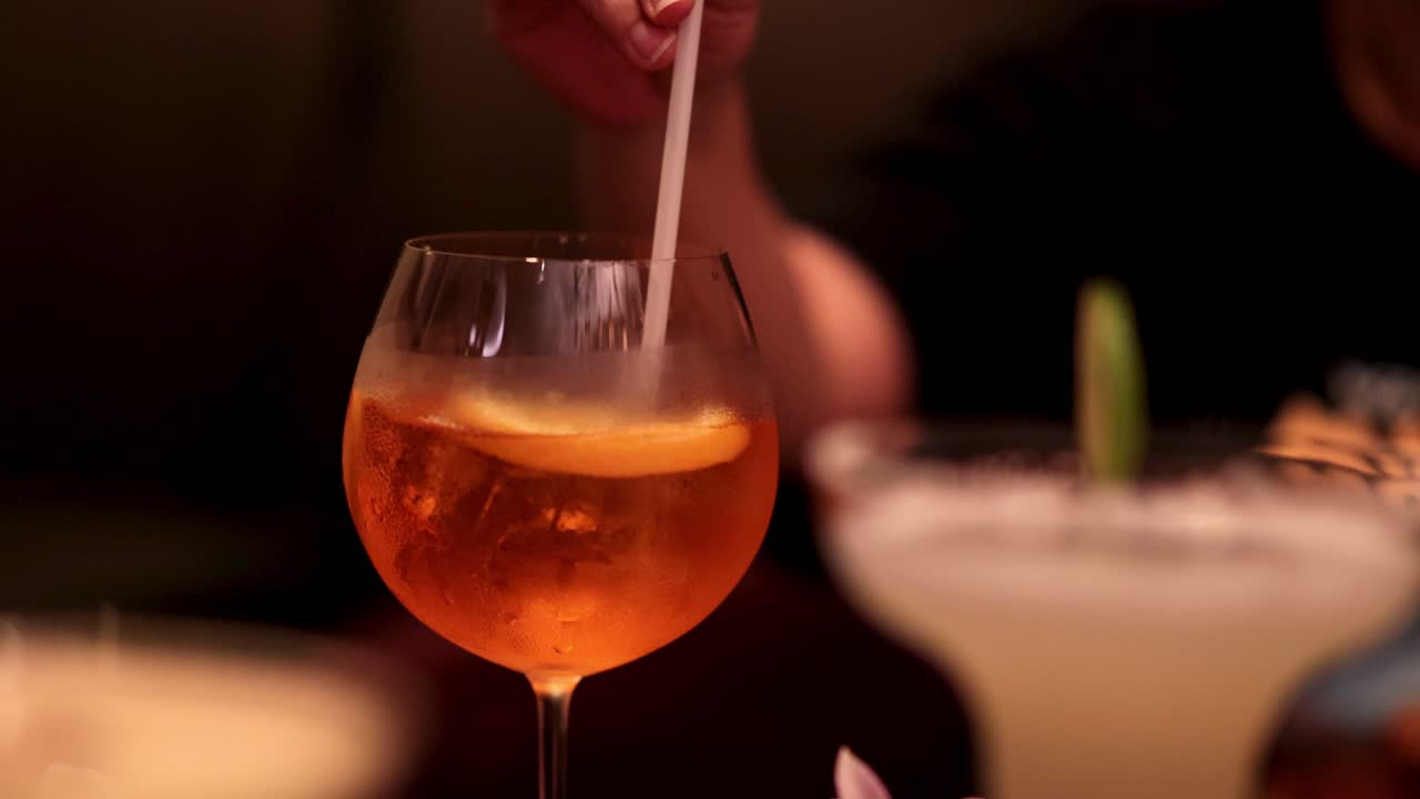 Mano che mescola un cocktail in un bar con luci soffuse