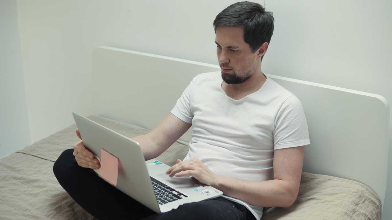 침대에 노트북으로 일하는 남자