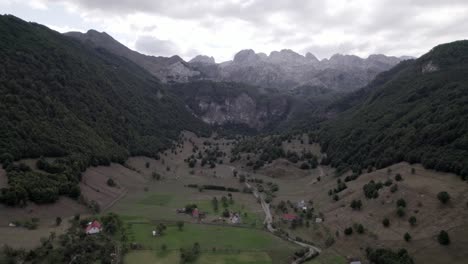 Video-Drone-Del-Avion-Frontal-Avanzando-Sobre-El-Valle-De-Lepushë-Sobre-El-Rio-Lëpusha,-El-Sh20-En-Albania,-Se-Pueden-Ver-Casitas-Del-Pueblo,-Un-Cielo-Algo-Nublado-Y-El-Rio-Seco