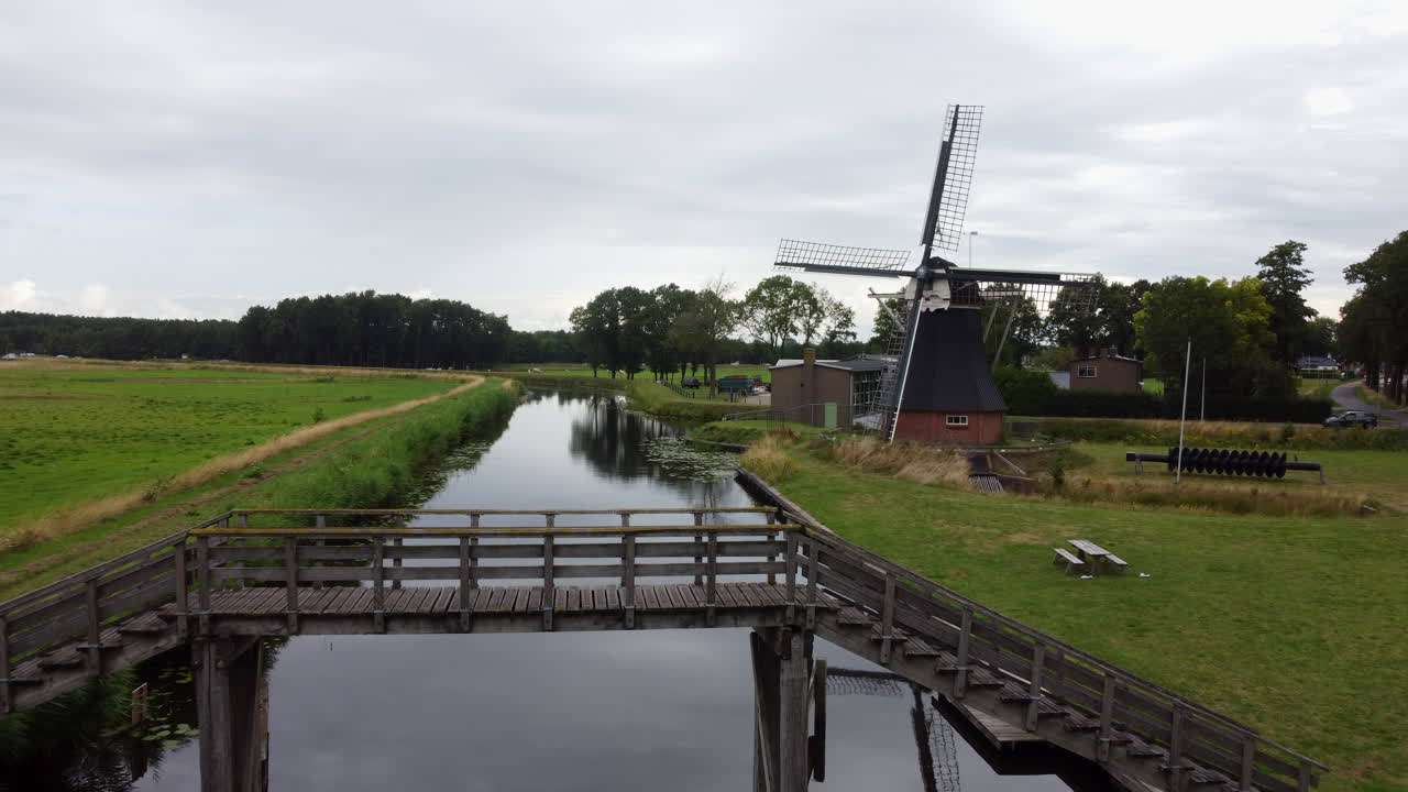 vista aérea viajando sobre el molino de agua y pasando a través de un pequeño puente de madera