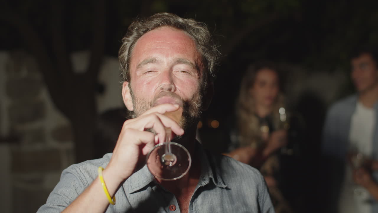 Slow motion of smiling man raising glass of champagne up