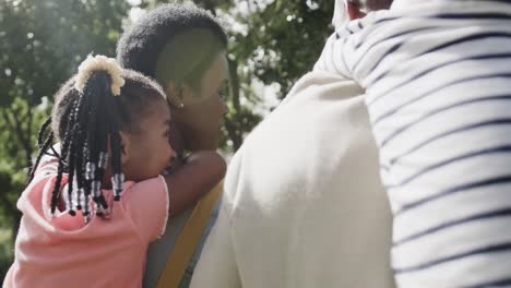 Feliz-Pareja-Afroamericana-Con-Hijo-E-Hija-Caminando-En-Un-Jardín-Soleado,-Cámara-Lenta