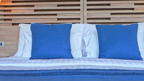 cama limpia hecha con almohadas azules y funda a rayas de lino en un hotel en filipinas, panorámica lenta a la derecha