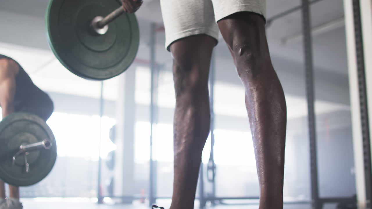 Lifting barbell, man working out in gym, focusing on strength training