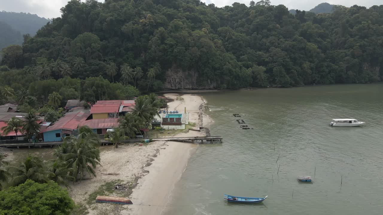 la densa selva tropical envuelve un pequeño complejo de playa en langkawi, malasia.