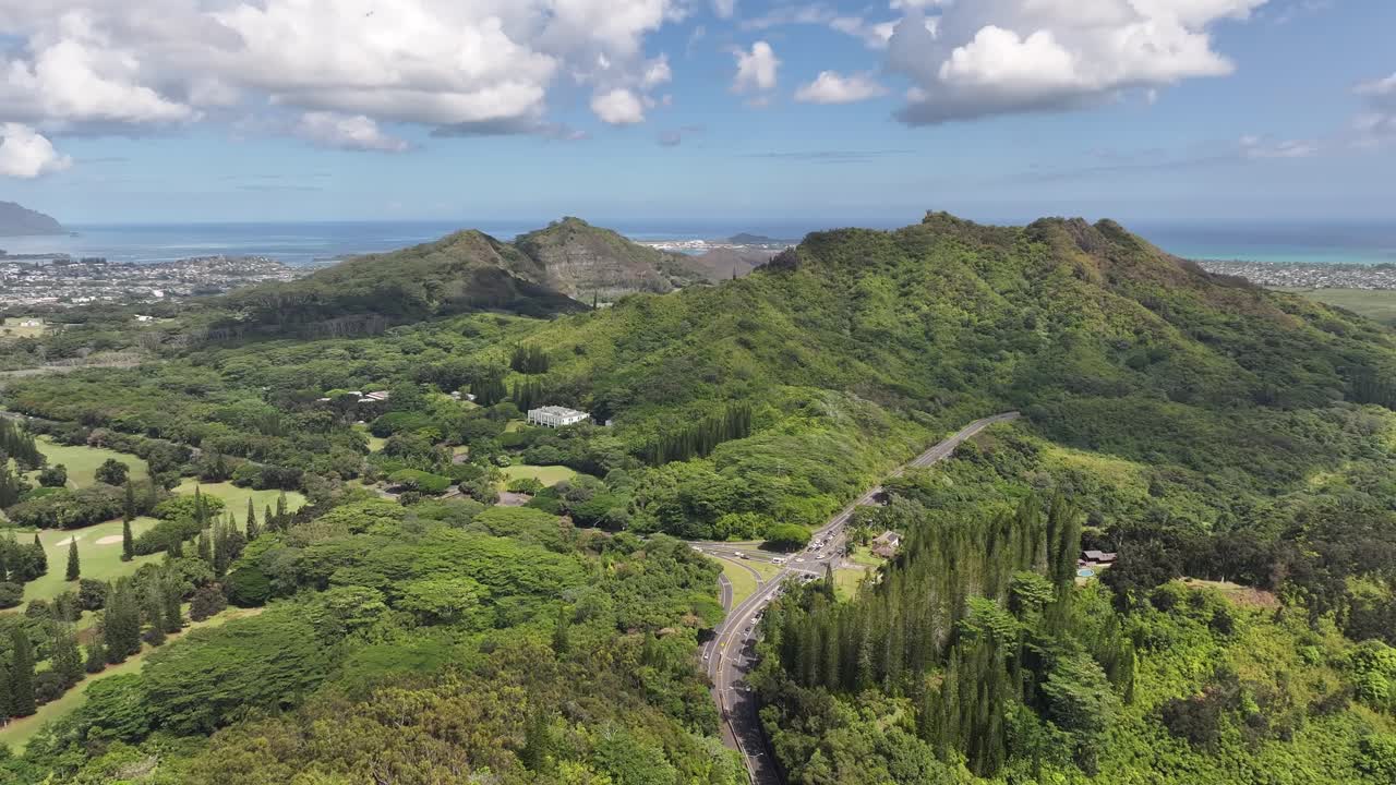 Aerial drone footage over Hawaii’s lush green mountains and tropical coastline, showcasing turquoise ocean waters, palm trees, scenic valleys, and vibrant island landscapes from above