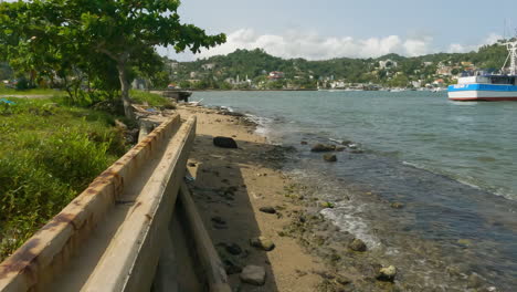 Ocean-Waves-On-Rocky-Shore-With-Moored-Boats-On-A-Sunny-Day-In-Samana,-Dominican-Republic