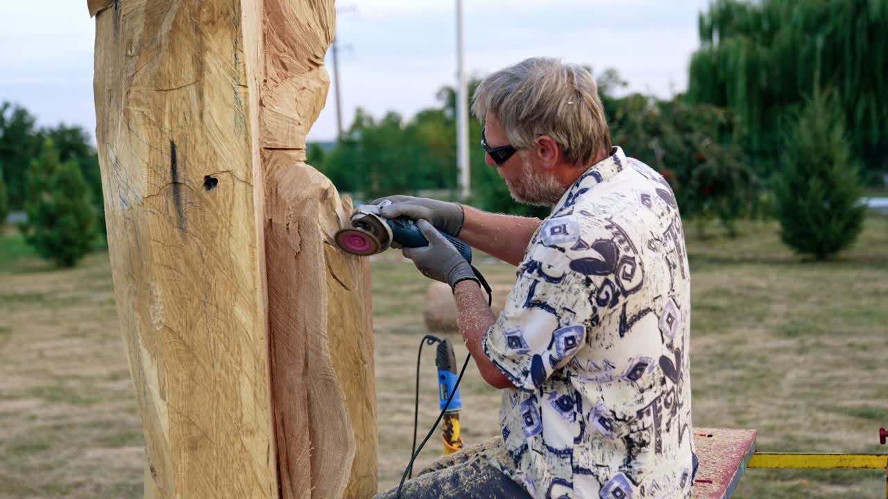 Adult Caucasian man making a wooden sculpture. Artist uses electric instrument in his work.