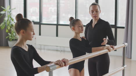 female teacher corrects the arm position of the gymnastic girl in ballet class 1