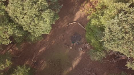 Drone-shot-overlooking-small-log-seating-circle-around-campfire