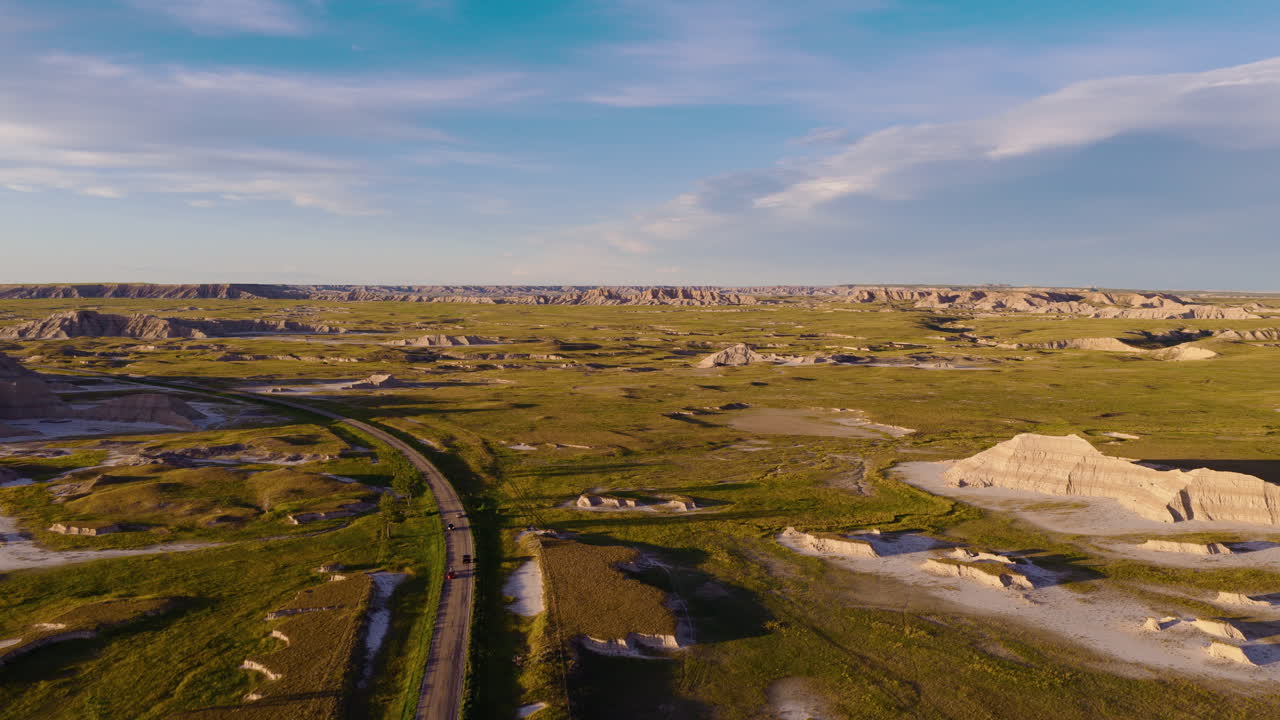Golden Light Shining on Rugged Badlands Road in Stunning Aerial View
