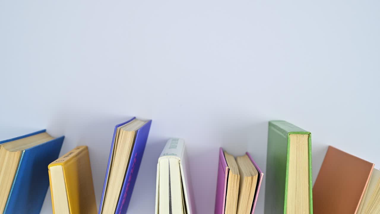 Vintage hardcover books in vibrant colors move on the table. Lat lay stop motion