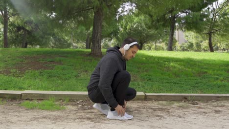 crouched runner puts on helmets and ties shoe