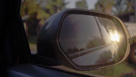 Slow-motion-clip-of-the-sunset-reflected-on-a-moving-car's-outside-mirror