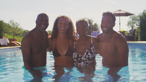 Multi-Generation-Family-With-Adult-Offspring-On-Summer-Holiday-Relaxing-In-Swimming-Pool-Together