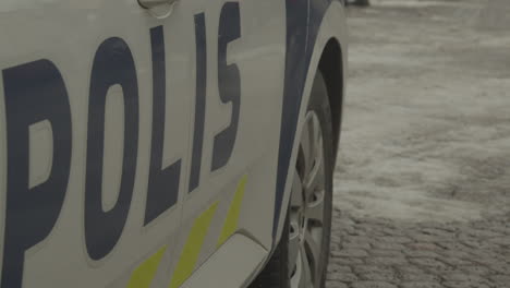 Side-view-of-a-Finnish-police-car-parked-on-a-snowy-paved-street