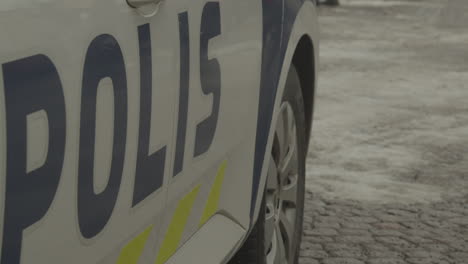 vista lateral de un coche de policía finlandés estacionado en una calle pavimentada con nieve