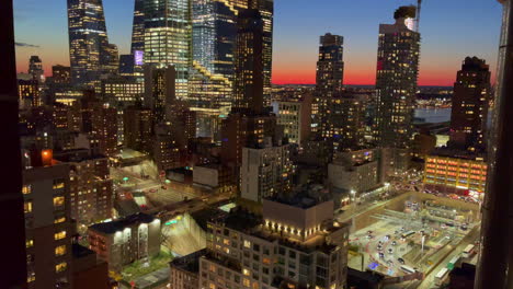 illuminated tall buildings as the horizon is colored by the setting sun in downtown new york city