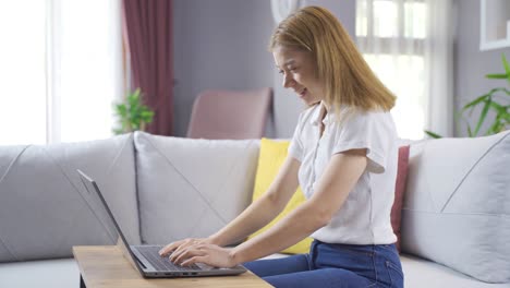 La-Ganadora-Emocionada-Y-Hermosa-Mira-La-Computadora-Portátil-Y-Celebra-El-éxito-En-Línea-Sentada-En-El-Sofá-De-Casa.