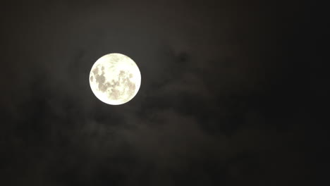 full glowing moon with clouds being blown by winds during storm at nights.