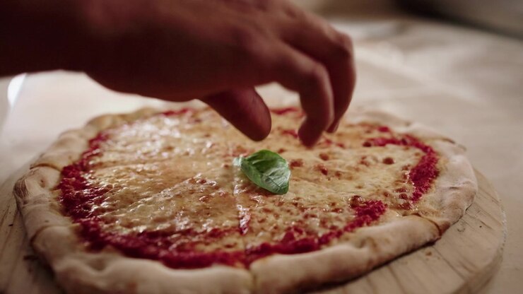 Chef che aggiunge foglie di basilico fresco a pizza Margherita cotta, rallentatore, dettaglio 07
