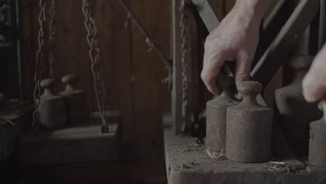 Vintage-scale-weights-being-placed-on-a-scale-in-a-barn,-static-medium-shot