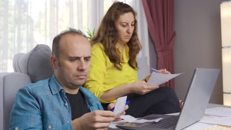 calculating the household budget, the husband and wife look at the bills.