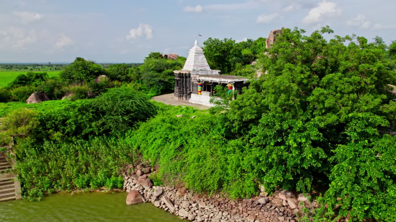 reveal shot of Thumbureshwara Devalayam with trees and granite hill at yelupu Gonda, Surampally, tekmal, medak district, Telangana, india. day time, semi orbit, drone shot, 4k.