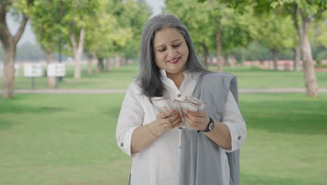 Happy-Indian-mother-counting-money-in-park