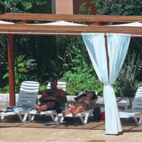 personas sentadas a la orilla de la piscina de un resort durante las vacaciones de verano