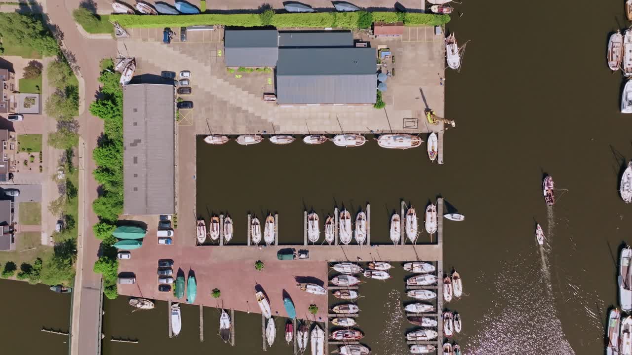 Aerial zoom in from high altitude over marina in Heeg with several boats docked, clear and sunny day