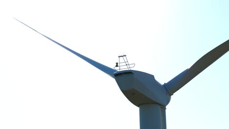 slow establishing shot of a red light flashing ontop of a wind turbine in france