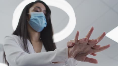 Woman-wearing-face-mask-sanitizing-her-hands-at-office