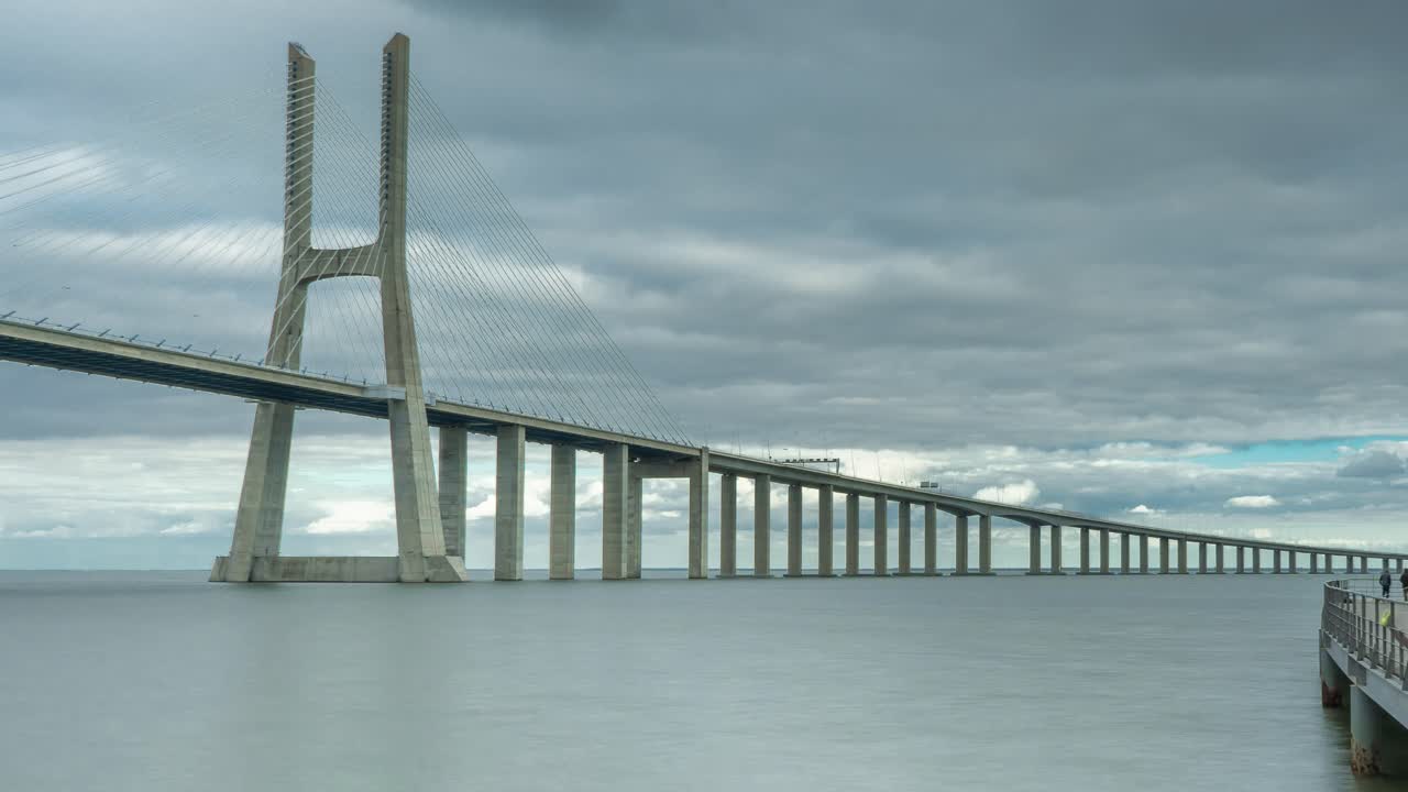 timelapse del puente vasco da gama en lisboa, portugal en un día nublado con una pasarela cercana